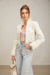 Woman wearing white cropped jacket with beaded details and ruffle trim