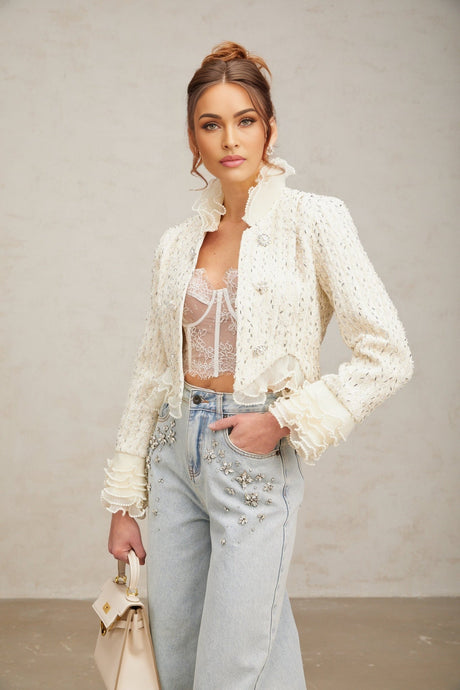 Woman wearing white cropped jacket with beaded details and ruffle trim