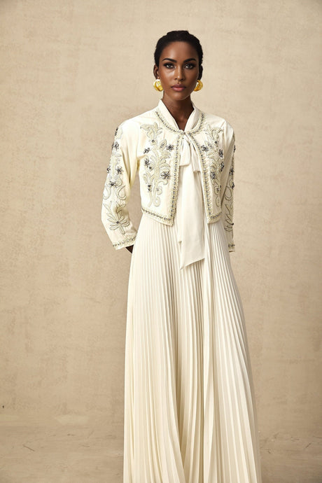 Woman wearing white embellished jacket and matching pleated dress set