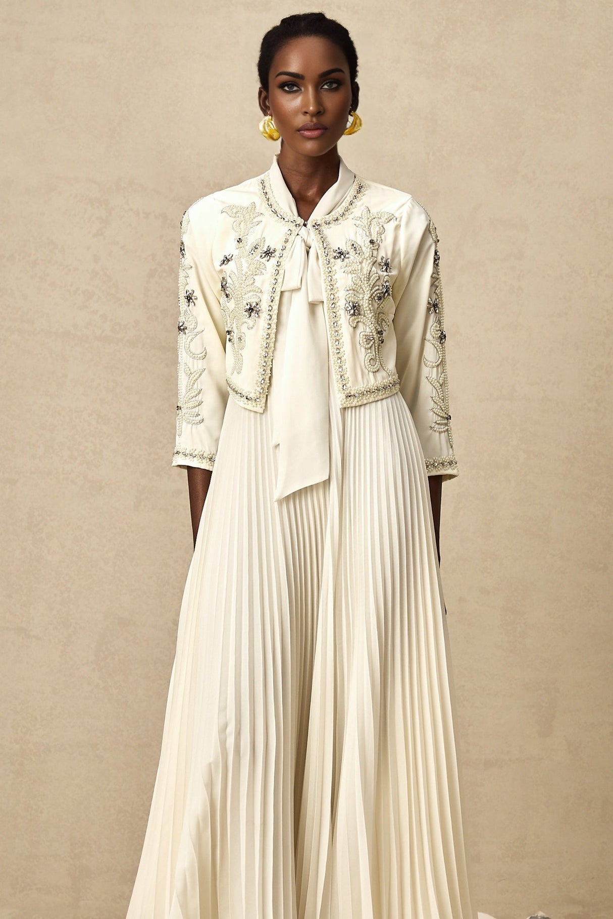 Woman wearing white embellished jacket with pleated details and matching dress Blanche brand formal outfit set