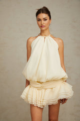 Woman wearing white halterneck mini dress with faux pearl embellishments