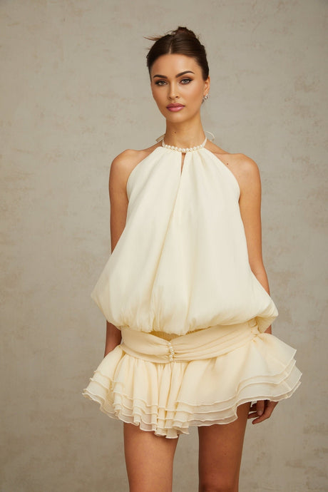 Woman wearing white halterneck mini dress with faux pearl embellishments