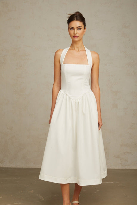 Woman wearing white halterneck pleated midi dress with flowy skirt and open back