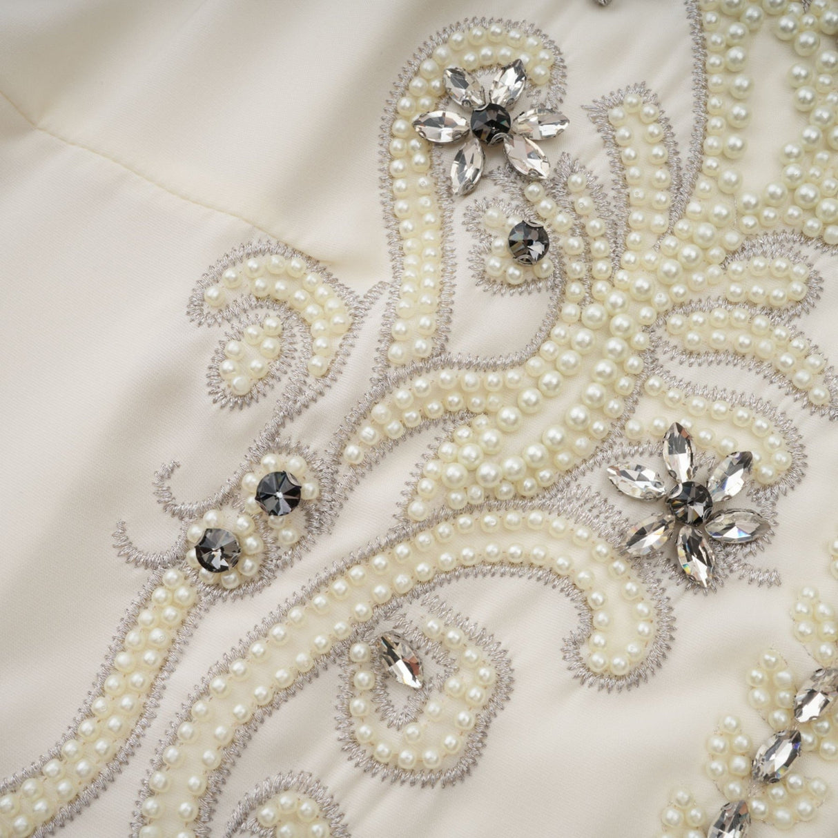 Woman wearing white jacket and dress set with pleated details and embellishments