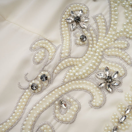 Woman wearing white jacket and dress set with pleated details and embellishments