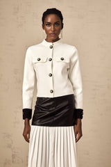 Woman wearing white knitted jacket with contrasting dark trim and button closure