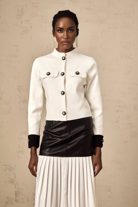 Woman wearing white knitted jacket with contrasting dark trim and button closure