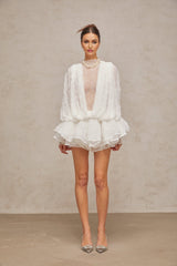 Woman wearing white lace matching set consisting of semi sheer top shorts and dress