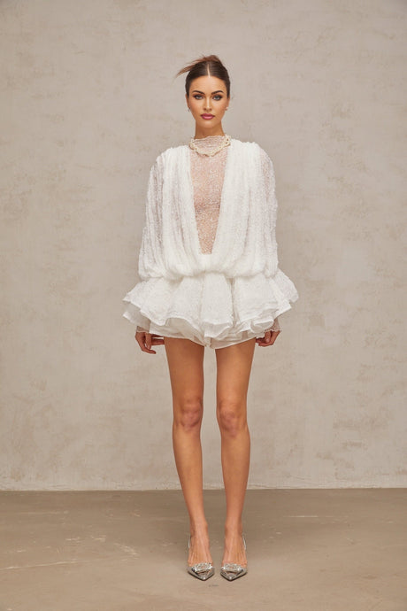 Woman wearing white lace matching set consisting of semi sheer top shorts and dress