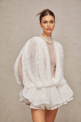 Woman wearing white lace matching set including semi sheer top shorts and dress
