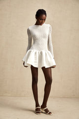 Woman wearing white lace mini dress with sheer panels and short sleeves