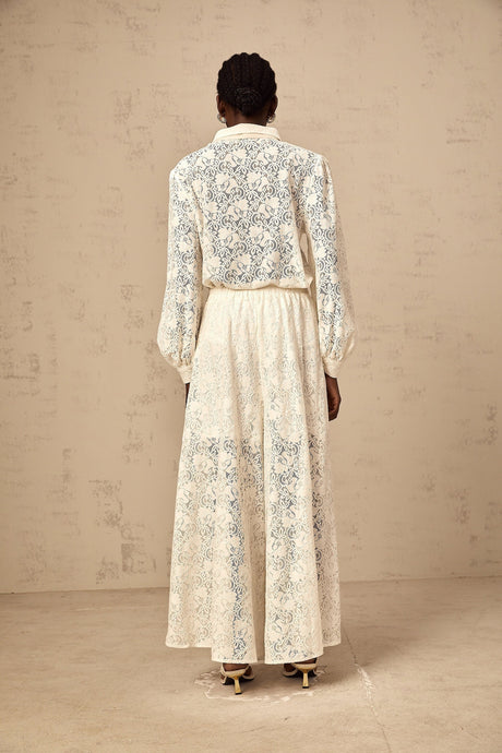 Woman wearing white lace shirt and matching trousers set with intricate guipure lace pattern