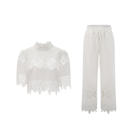 Woman wearing white lace trim cropped top and matching trousers set featuring cutout details