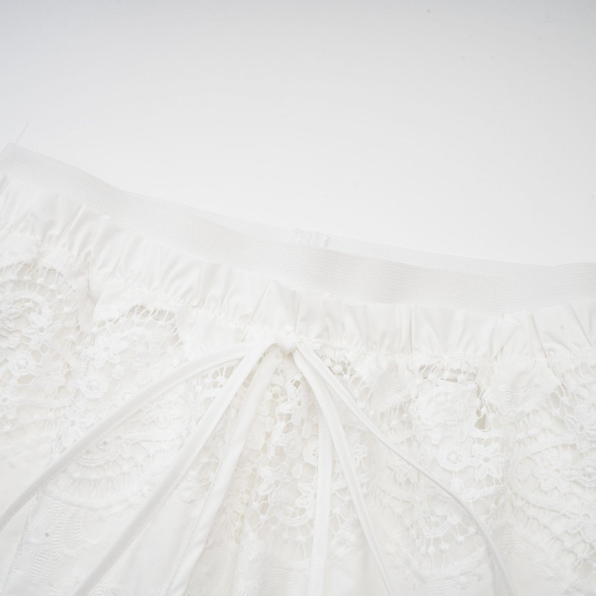 Woman wearing white lace trim cropped top and matching trousers set with cutout details