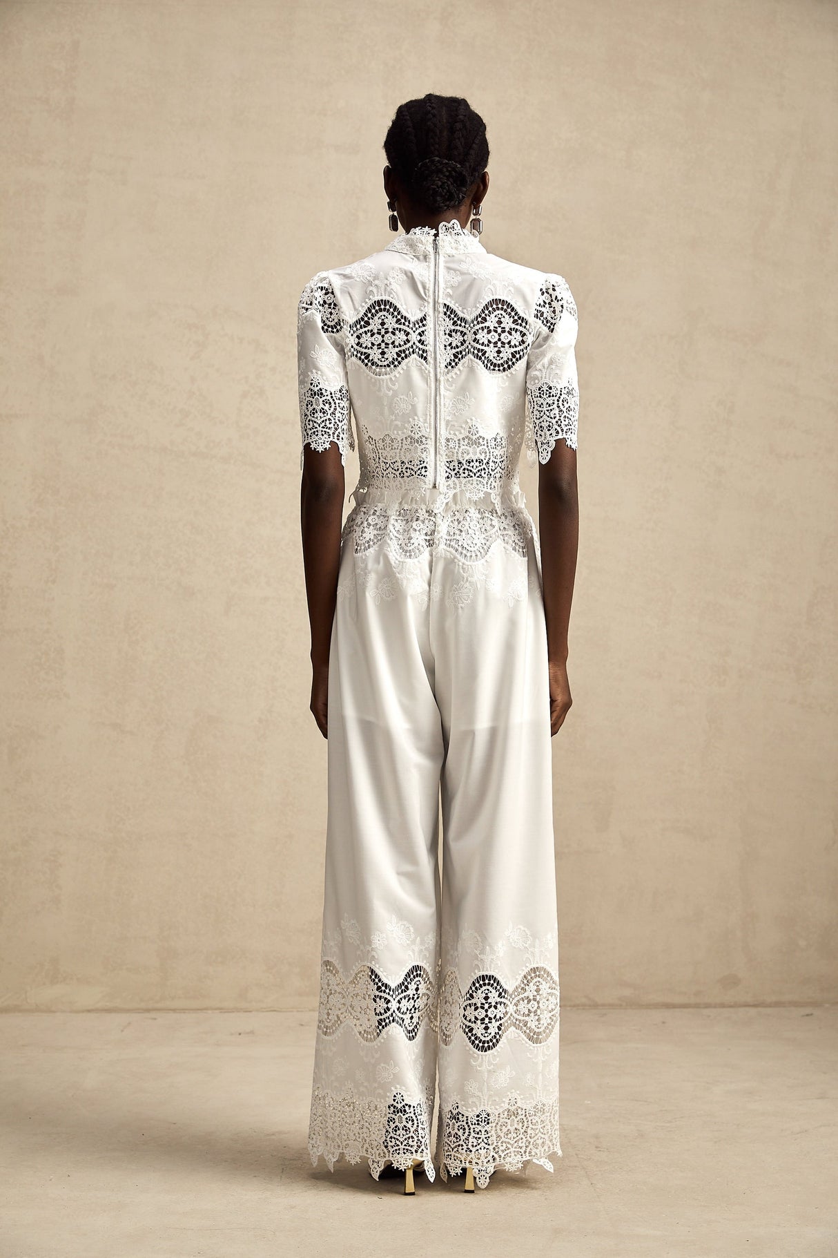 Woman wearing white lace trim cropped top and matching trousers with cutout details Raphaelle matching set