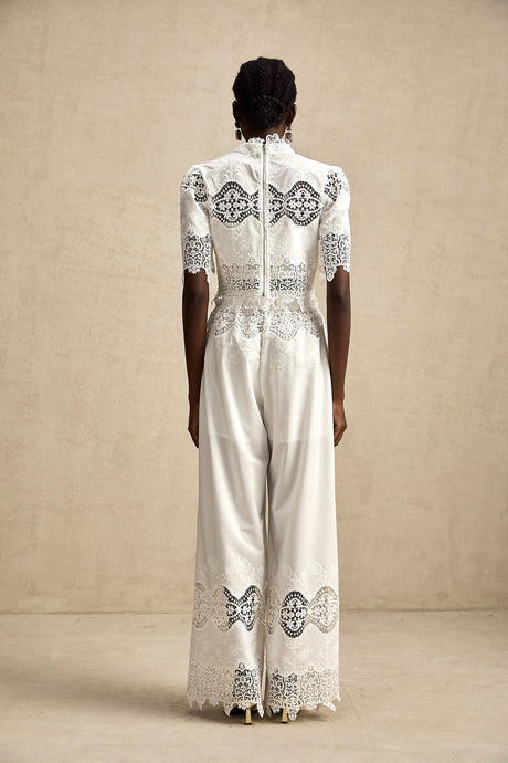 Woman wearing white lace trim cropped top and matching trousers with cutout details Raphaelle matching set