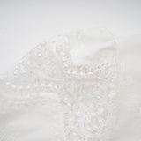 Woman wearing white lace trimmed cropped top and matching trousers with cutout details