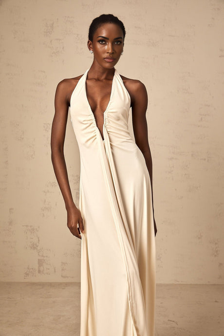 Woman wearing white long flowing maxi dress with deep V neckline and draped fabric detail