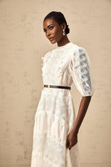 Woman wearing white midi dress with lace trim panels and belt at waist