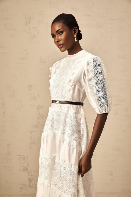 Woman wearing white midi dress with lace trim panels and belt at waist