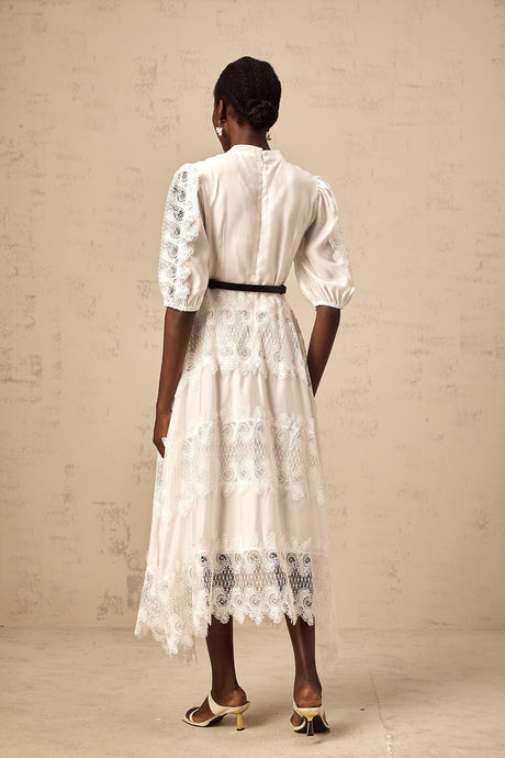 Woman wearing white midi dress with lace trim panels and belt at waist