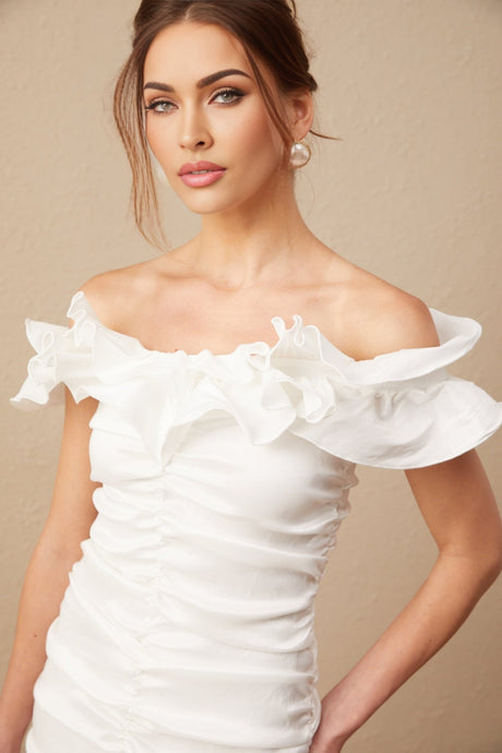 Woman wearing white off shoulder mini dress with ruffled details