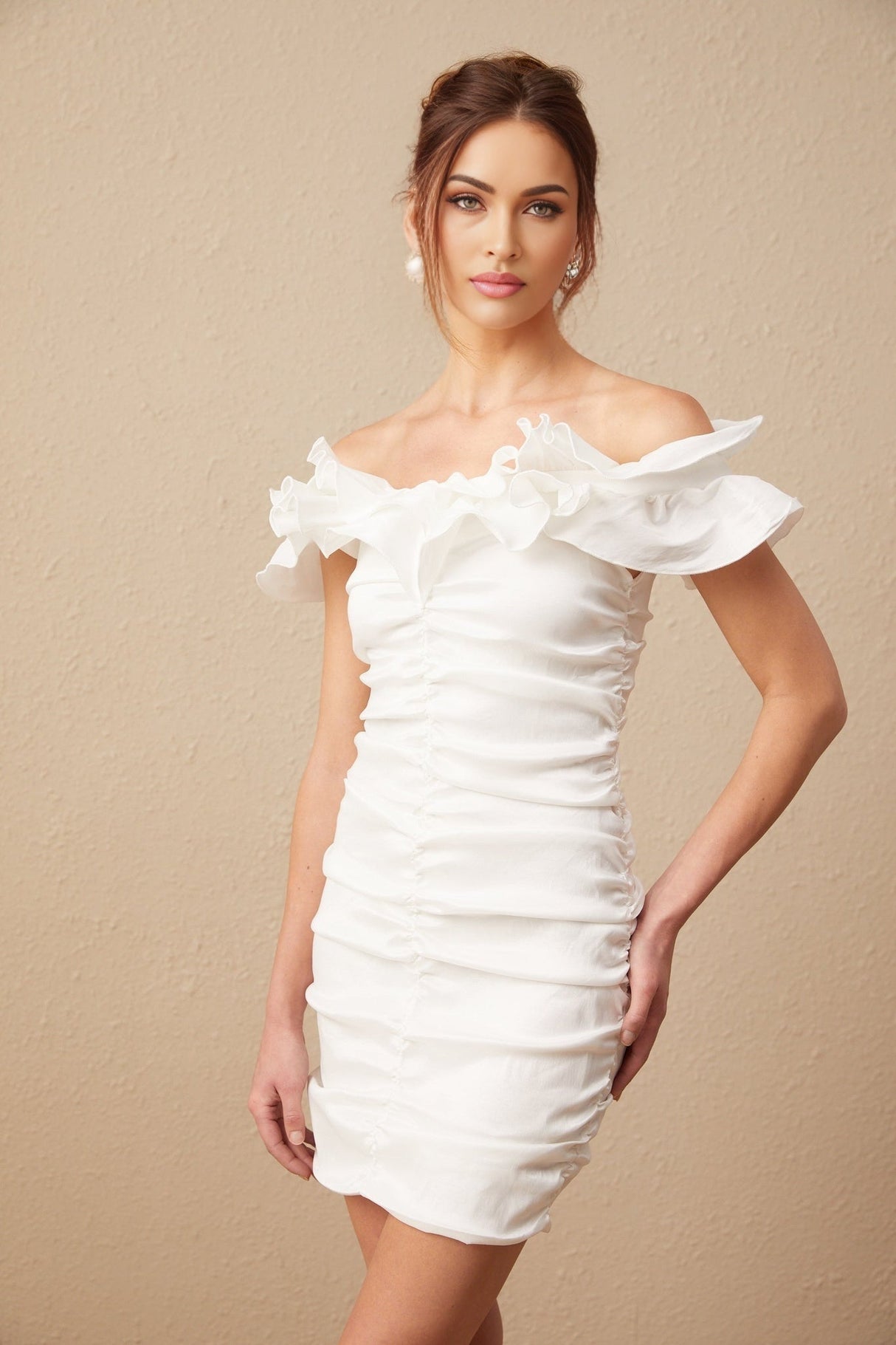 Woman wearing white off shoulder mini dress with ruffled details