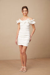 Woman wearing white off shoulder mini dress with ruffled details