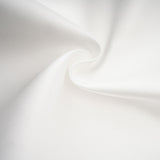 Woman wearing white offshoulder maxi dress with panelled design standing against plain background