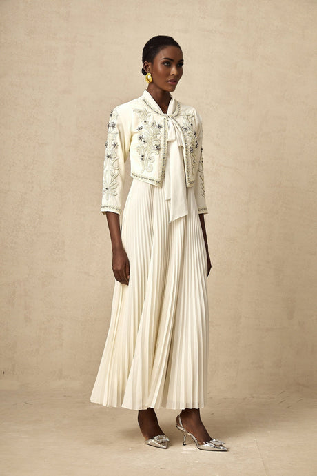 Woman wearing white pleated dress with matching embellished jacket formal outfit set