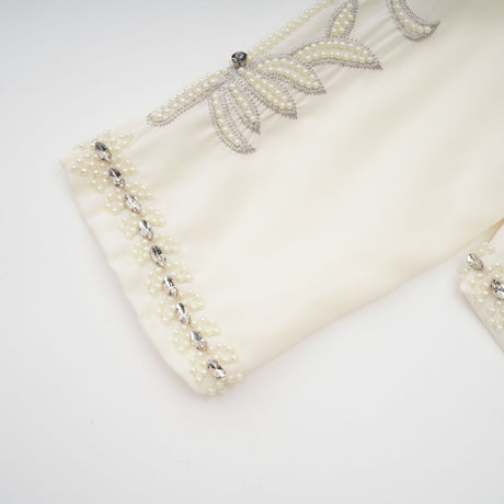Woman wearing white pleated jacket and dress set with embellishments Blanche design matching outfit formal attire