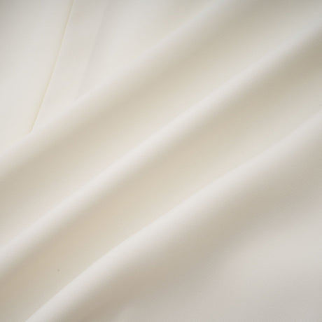Woman wearing white pleated jacket and dress set with embellishments Blanche design