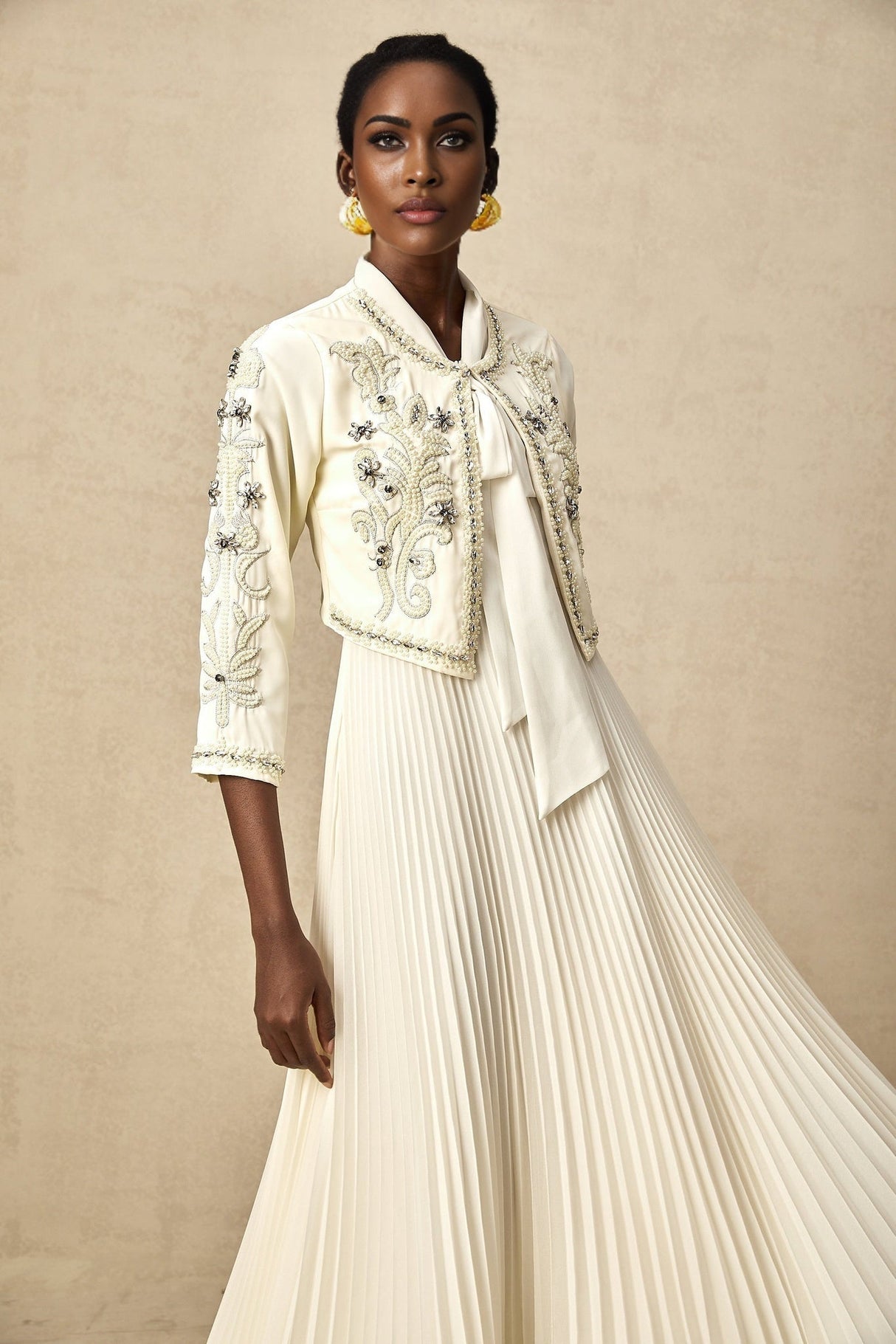 Woman wearing white pleated jacket and matching dress with embellishments Blanche outfit set