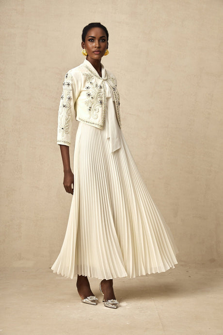 Woman wearing white pleated jacket and matching dress with embellishments Blanche set formal attire