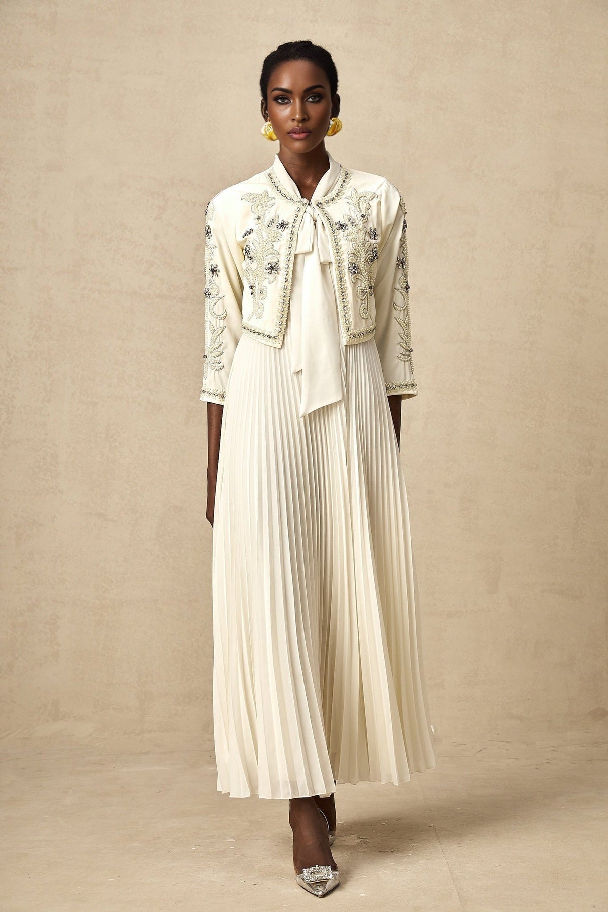 Woman wearing white pleated jacket and matching dress with embellishments Blanche set