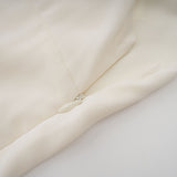 Woman wearing white pleated jacket and matching dress with embellishments elegant formal outfit set