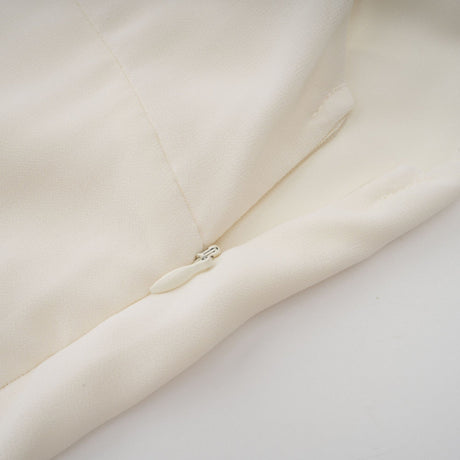 Woman wearing white pleated jacket and matching dress with embellishments elegant formal outfit set