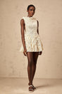 Woman wearing white semisheer lace mini dress with creased texture standing against plain background