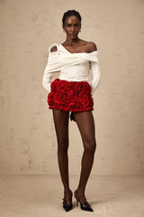Woman wearing white sleeveless asymmetric top with twisted design across torso