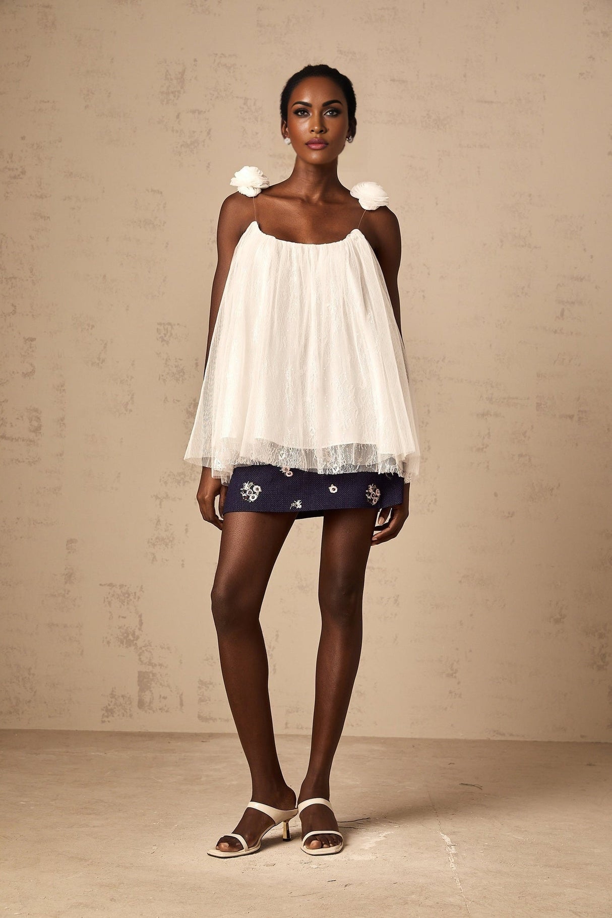 Woman wearing white sleeveless top with floral mesh applique detail