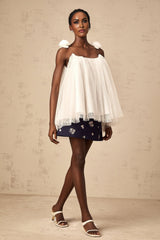 Woman wearing white sleeveless top with floral mesh overlay and flower appliques