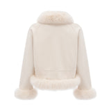 Woman wearing white suede short coat with fur trim and padded design standing against plain background