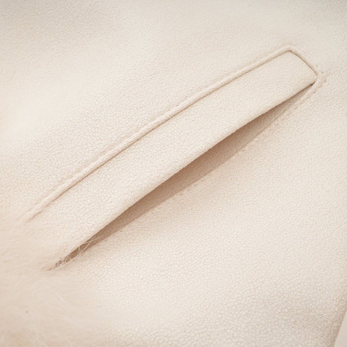 Woman wearing white suede short coat with fur trim and padded design standing against plain background