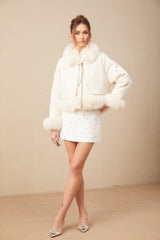 Woman wearing white suede short coat with fur trim and padded design