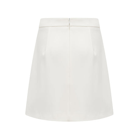 Woman wearing white twopiece outfit with crystal embellishments consisting of a sleeveless top and matching skirt