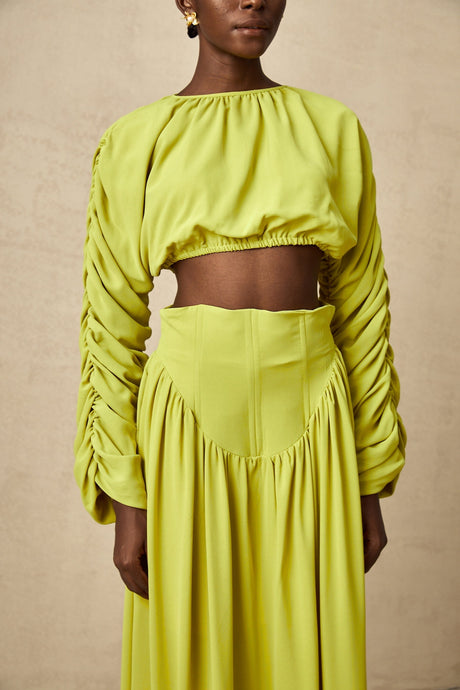 Young girl wearing a green smocked top and matching skirt set called Emilie