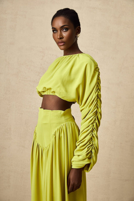 Young girl wearing a matching green smocked top and skirt set named Emilie featuring a floral pattern and ruffle details