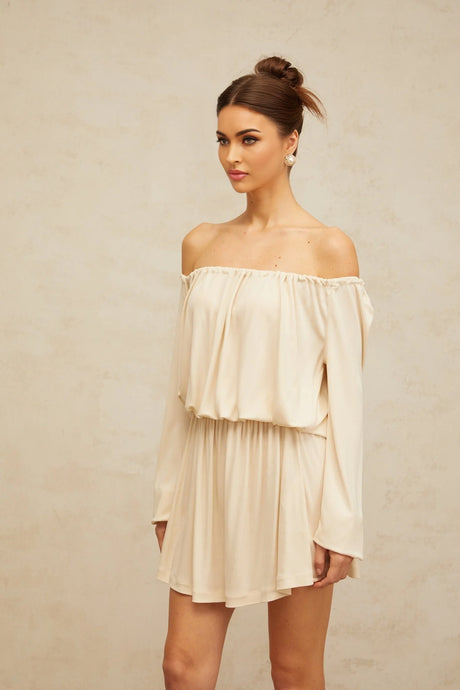 Young woman wearing a beige mini dress with structured design details standing against a neutral background