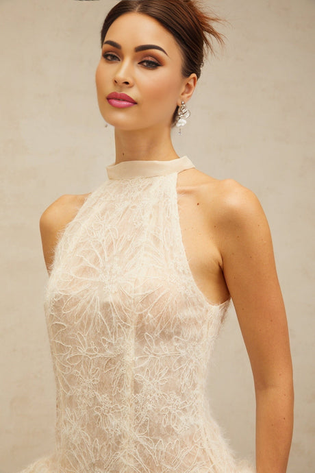 Young woman wearing a beige textured mini dress with puff sleeves standing against a neutral background