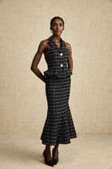 Young woman wearing a black and white checked tweed matching set consisting of a sleeveless vest top and skirt